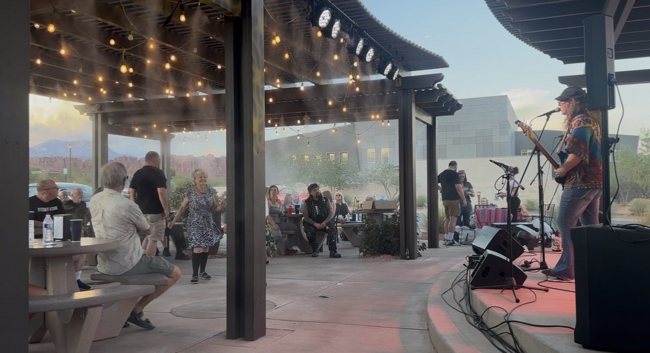 Band performing at dusk with mountain views and a dancing crowd