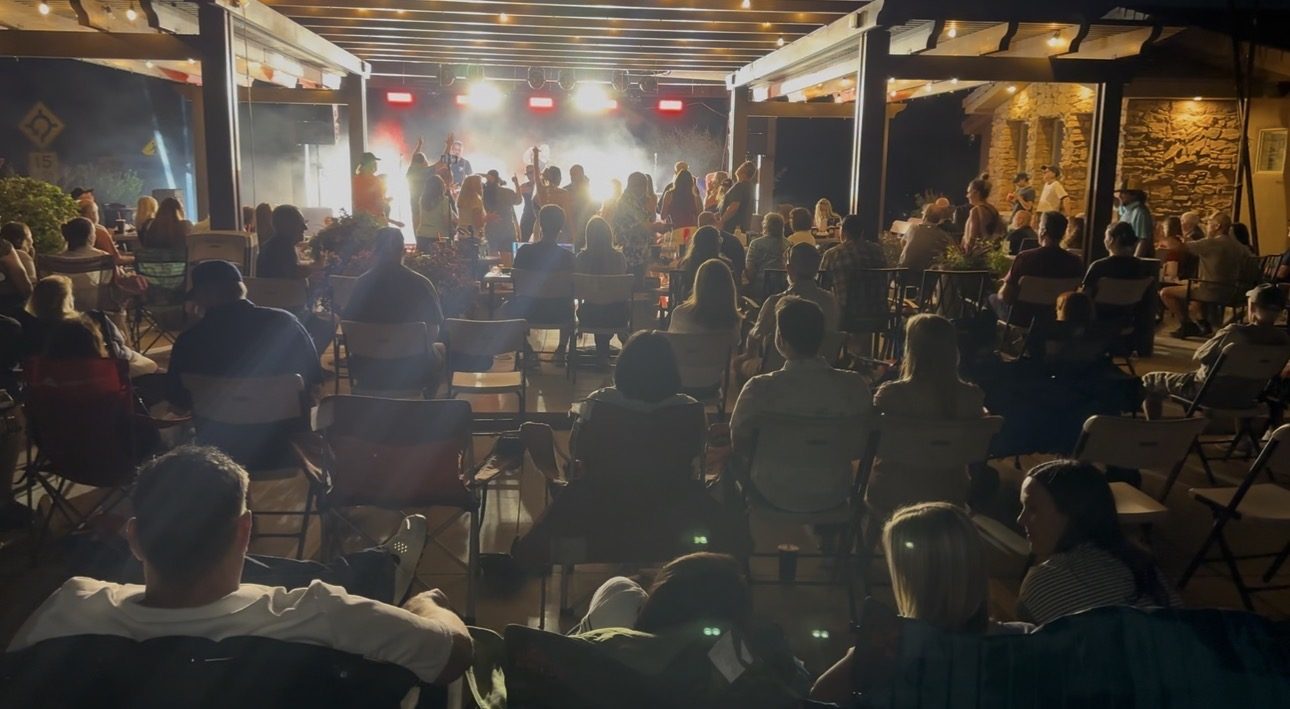 Crowd watching a band perform under red stage lighting at night