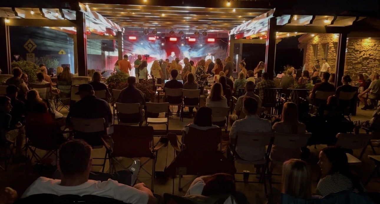 Band performing under red and blue lights as the crowd watches at night