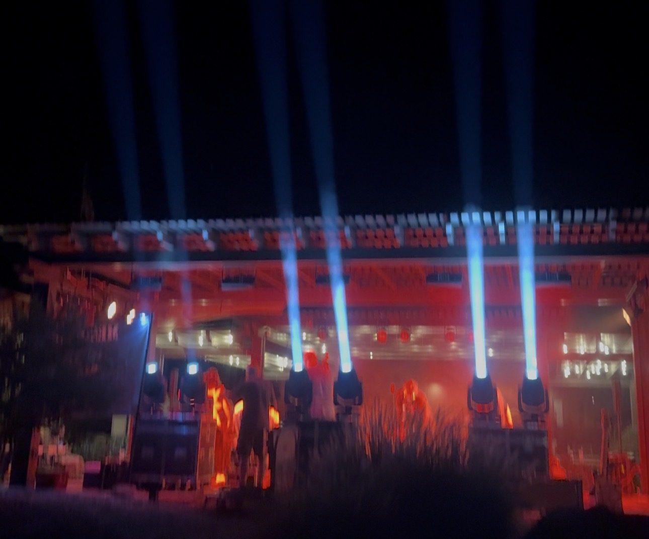 Stage lighting beams cutting through the night sky at a SUMAC show